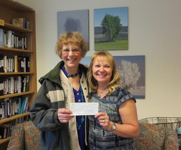   Bev Abbs presents a $100 cheque to Tracy Haddow, Program Director of the 100 Mile District Hospice.